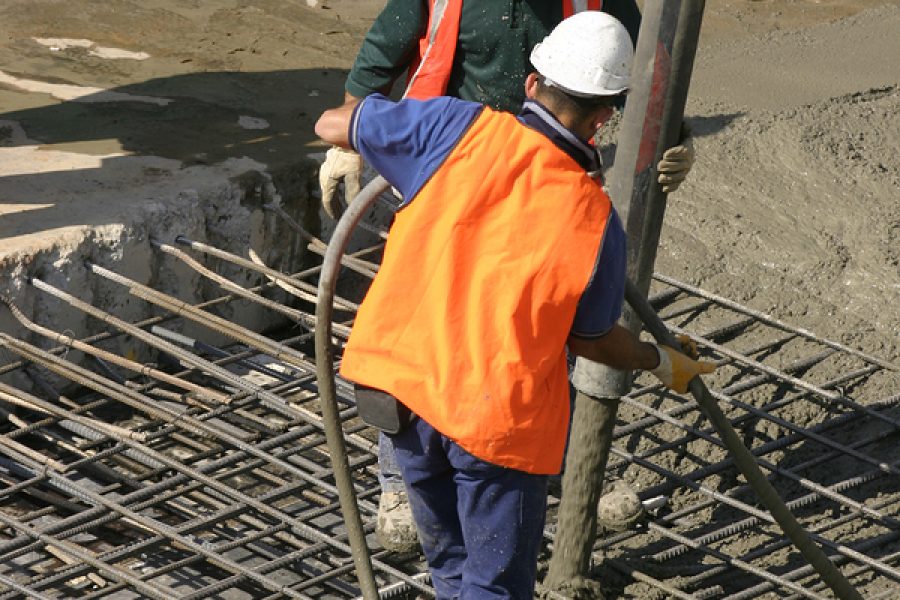 Workers Standing On Thick Steel Mesh And Pouring Concrete